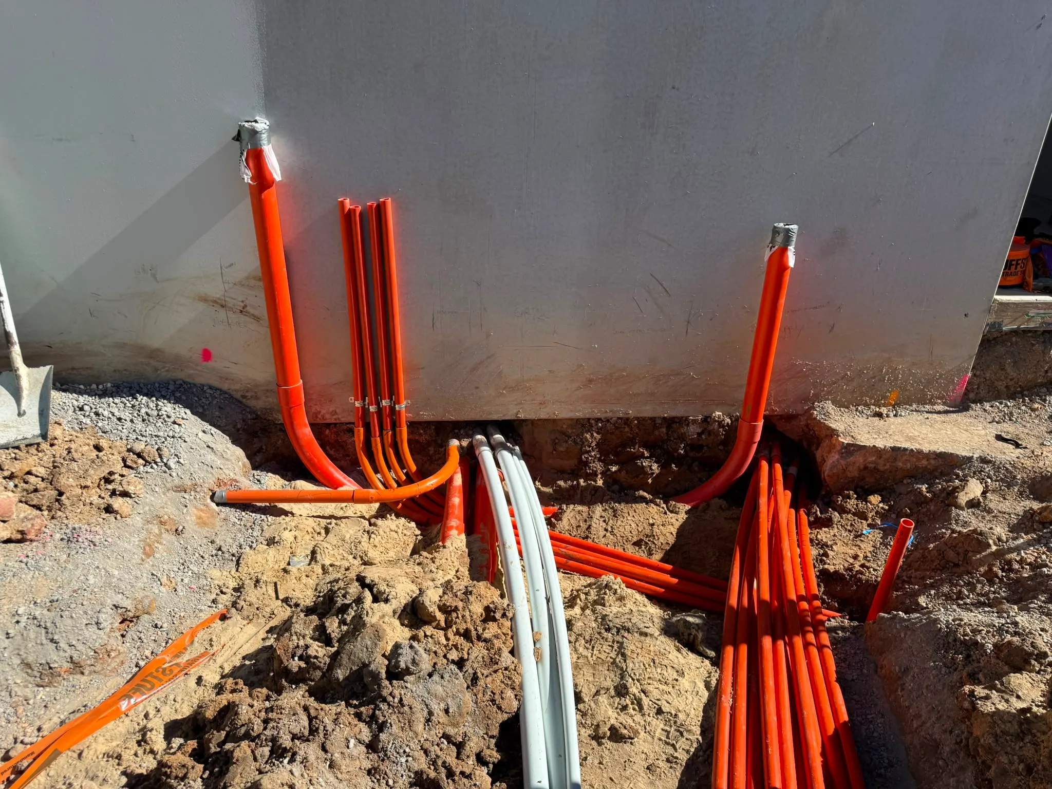 Orange conduits laid in a trench for new underground service mains
